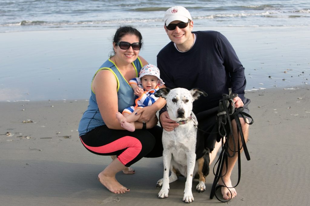 Family beach photo with baby and dog.