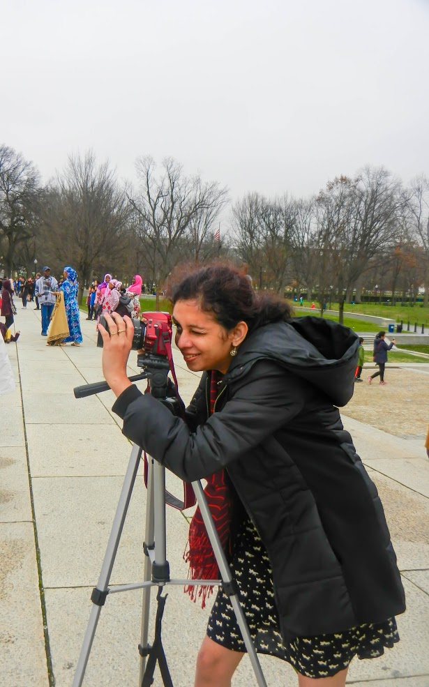 Woman photographing people with tripod.