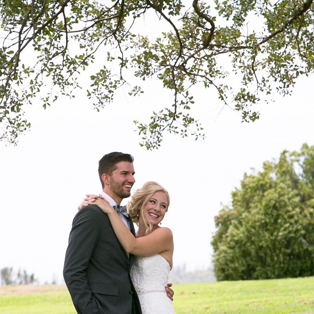 Happy bride and groom embracing outdoors.