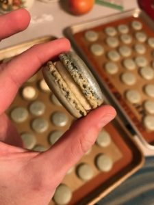 A person holding a macaroon in their hand.