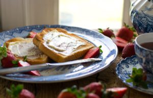 A plate with two pieces of bread and strawberries on it.