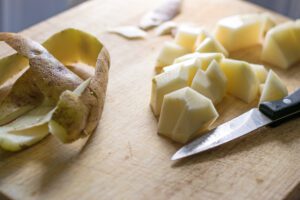 A cutting board with some cut up potatoes and a knife